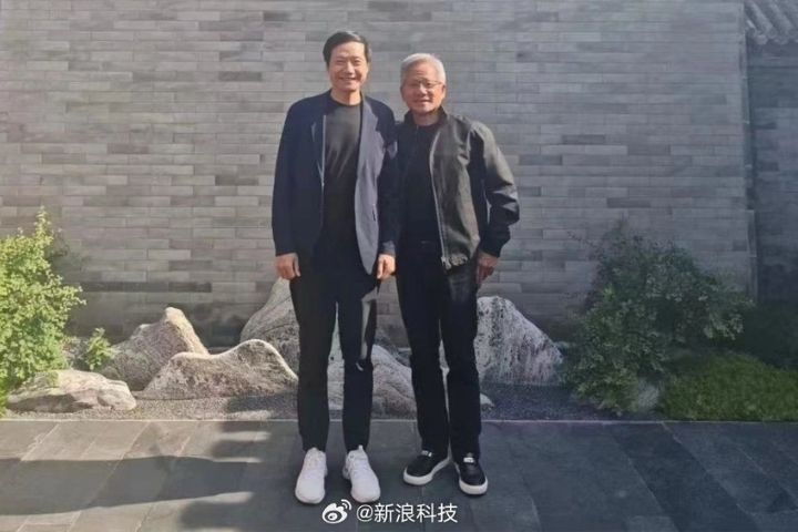 北京氣溫高達35℃，黃仁勳仍以招牌黑色皮衣現身，與雷軍合影。圖/取自新浪科技微博