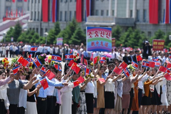 習近平與妻子彭麗媛乘車轉往金日成廣場，途中北韓民眾沿途夾道歡迎。圖/取自新華社
