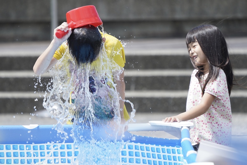 小朋友8日在台北花博公園圓山園區戲水區直接舀起一大瓢水澆頭，消消暑氣。圖/中央社
