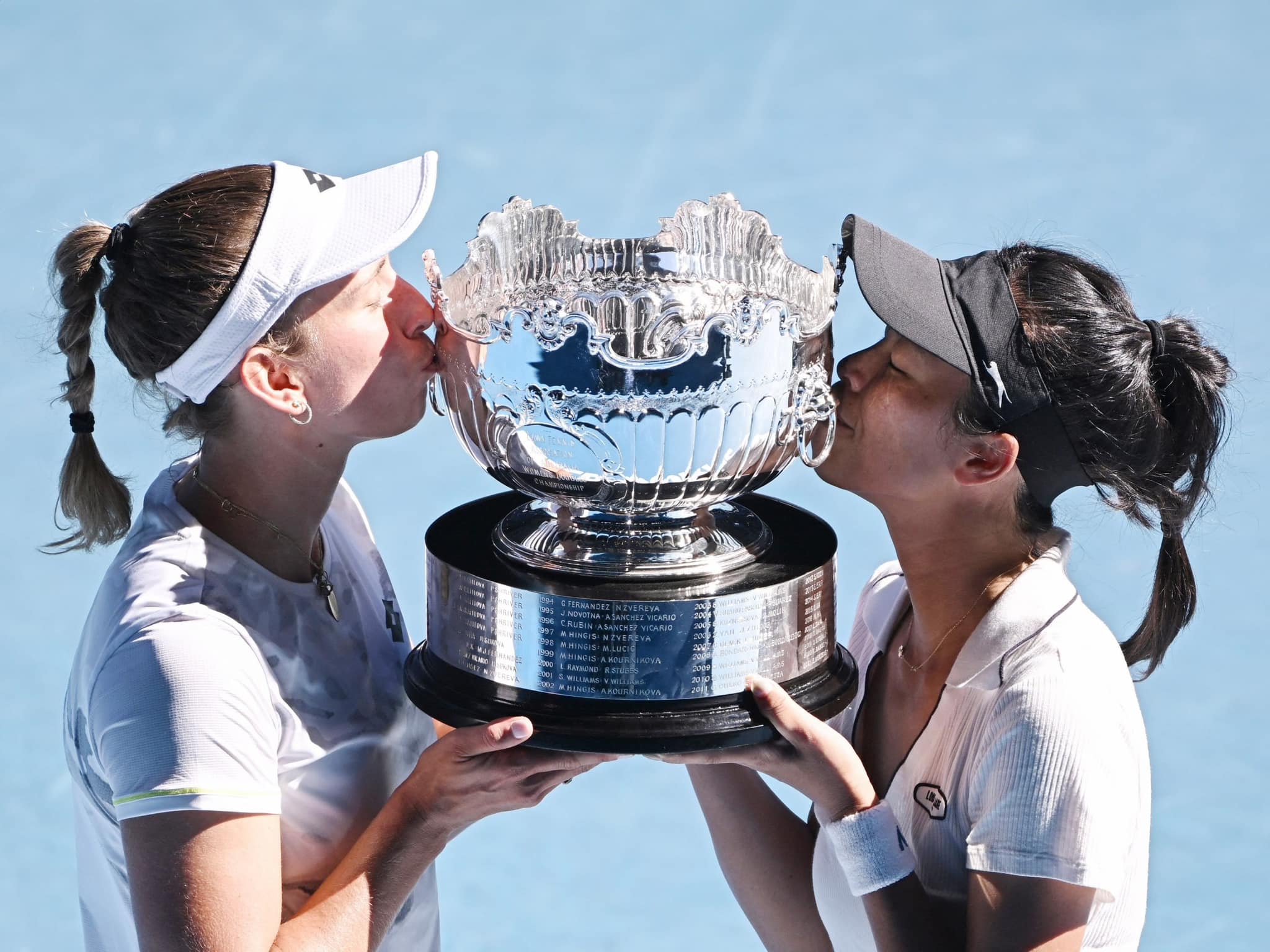 謝淑薇（右）與比利時搭檔梅丹斯（左）賽後開心親吻冠軍金盃。圖/取自澳洲網球公開賽網站