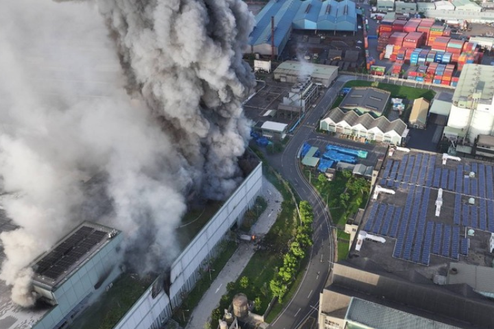 高雄市小港區三元能源公司建築14日清晨5時許發生火警，現場建築冒出大量濃煙，經消防員布水線灌救，火勢持續控制中。（高雄市政府消防局提供）圖/中央社