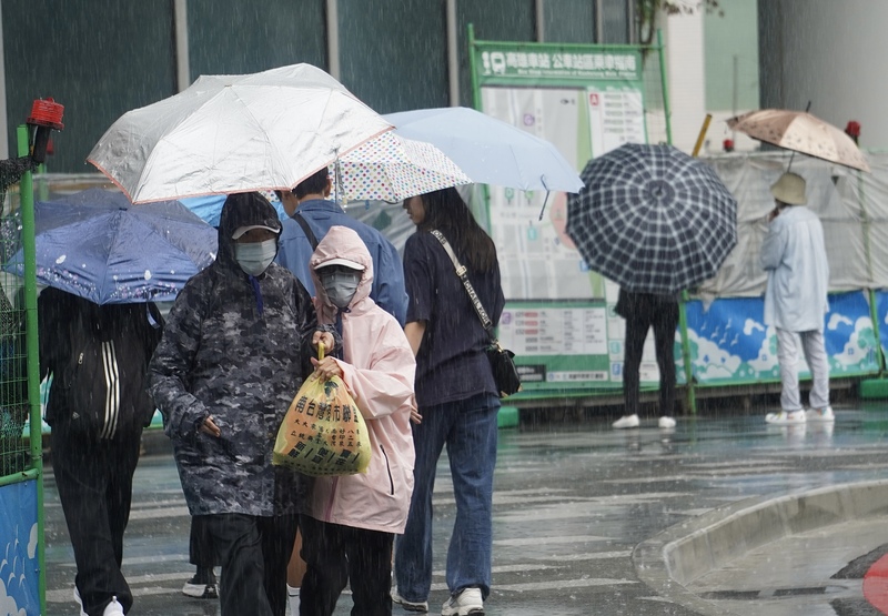 中央氣象署28日發布豪雨特報，鋒面通過，易有短延時強降雨。圖為28日上午高雄市三民區下起一陣大雨，民眾撐傘走在市區街頭。圖/中央社