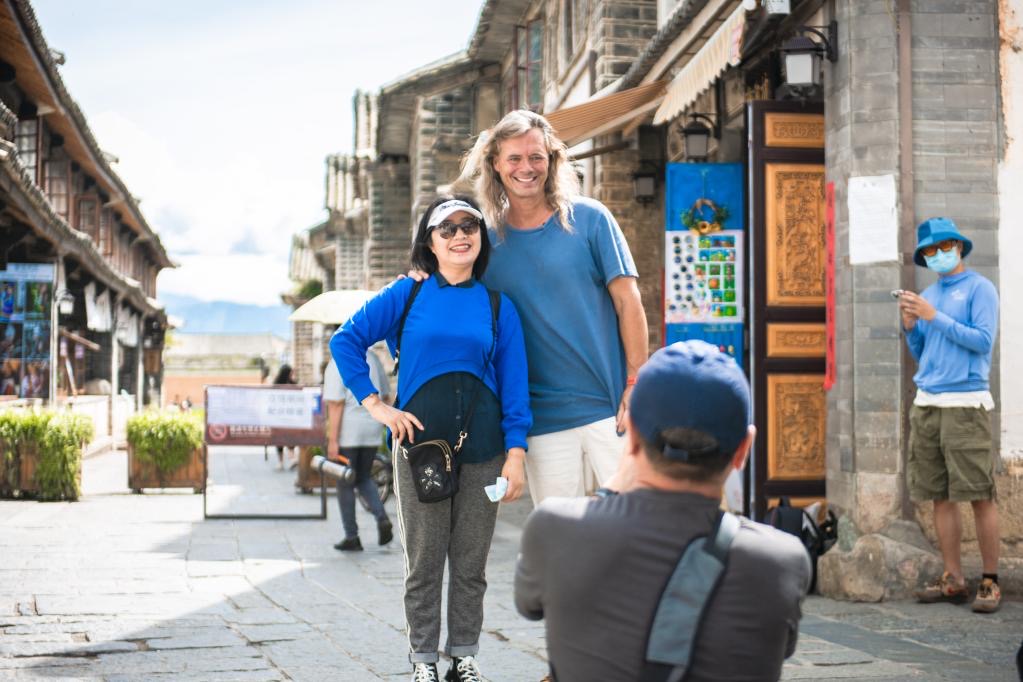 美國人林登在喜洲古鎮與遊客合照。圖/取自新華社