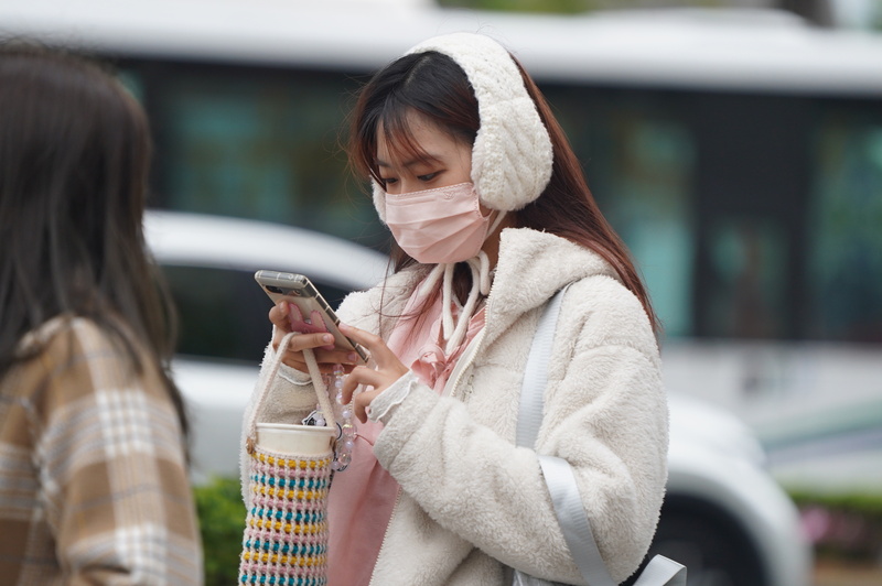 強烈大陸冷氣團來襲，今晨有感降溫。圖為民眾在台北市士林區穿戴保暖耳罩禦寒。中央社