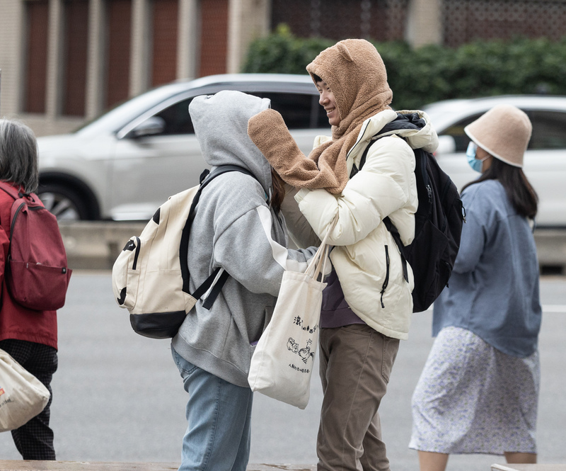 今天冷氣團減弱，氣溫可望回暖。圖為台北市中正區街頭，民眾穿外套、戴帽子禦寒。中央社