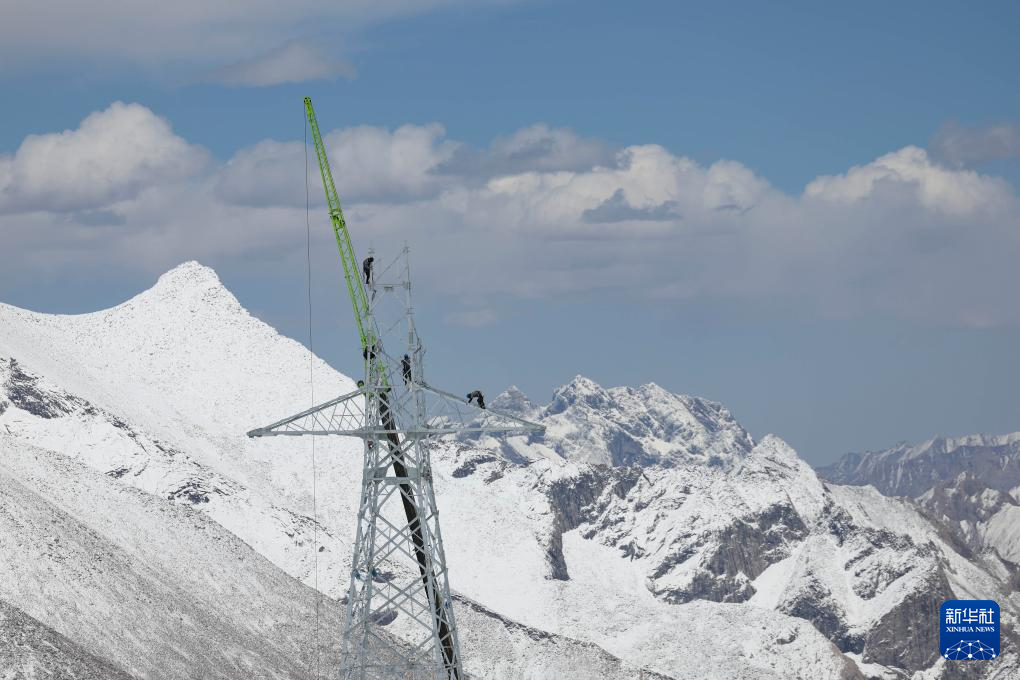 今年4月25日崑崙山仍白雪皚皚，工人在位於新疆和田地區崑崙山區的鐵塔上作業。圖/新華社