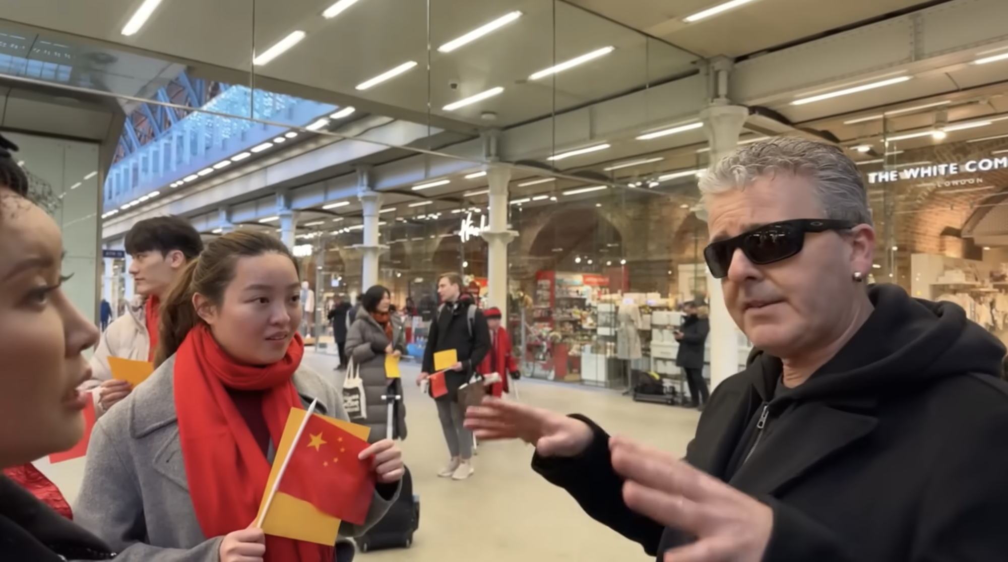 手持五星旗的中國人士與英國網紅鋼琴家卡瓦納以肖像權為導火線在倫敦聖潘克拉斯火車站爆發衝突。圖／翻攝自Dr K Boogie Woogie (Brendan Kavanagh)  YouTube影片