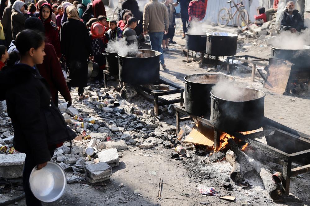 上月底在加薩北部難民營，人們等待領取食物。圖/取自新華社