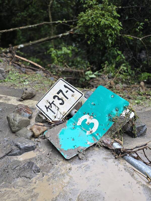  新竹縣北埔鄉通往苗栗縣南庄鄉的竹37-1線道路4日受雨勢影響，落石崩塌、路面泥濘，路旁標示牌毀損傾倒。圖/北埔鄉公所提供、中央社
