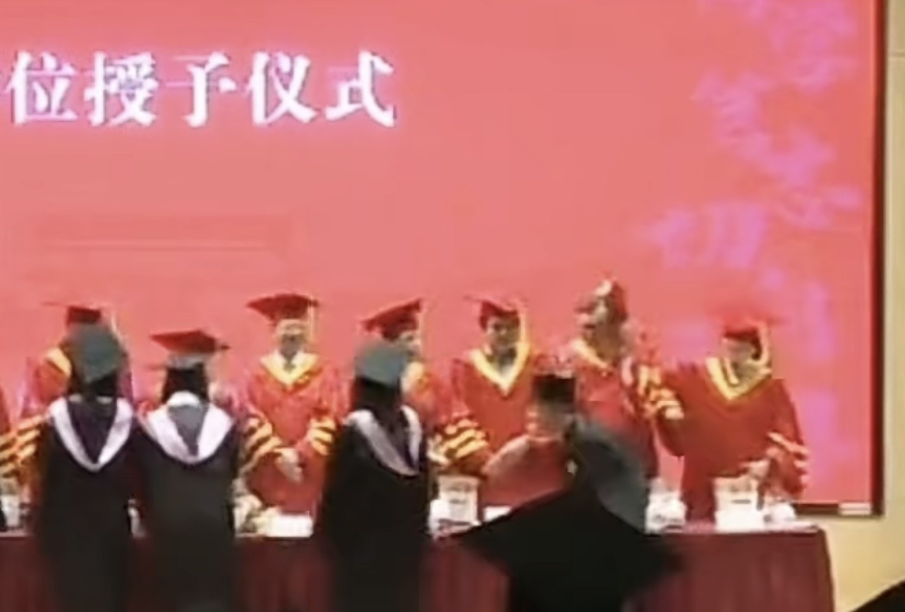 上海復旦大學畢業典禮上舉行學位授予儀式時，一名台生竟然對著頒發畢業證書的老師揮拳。圖/截自微博