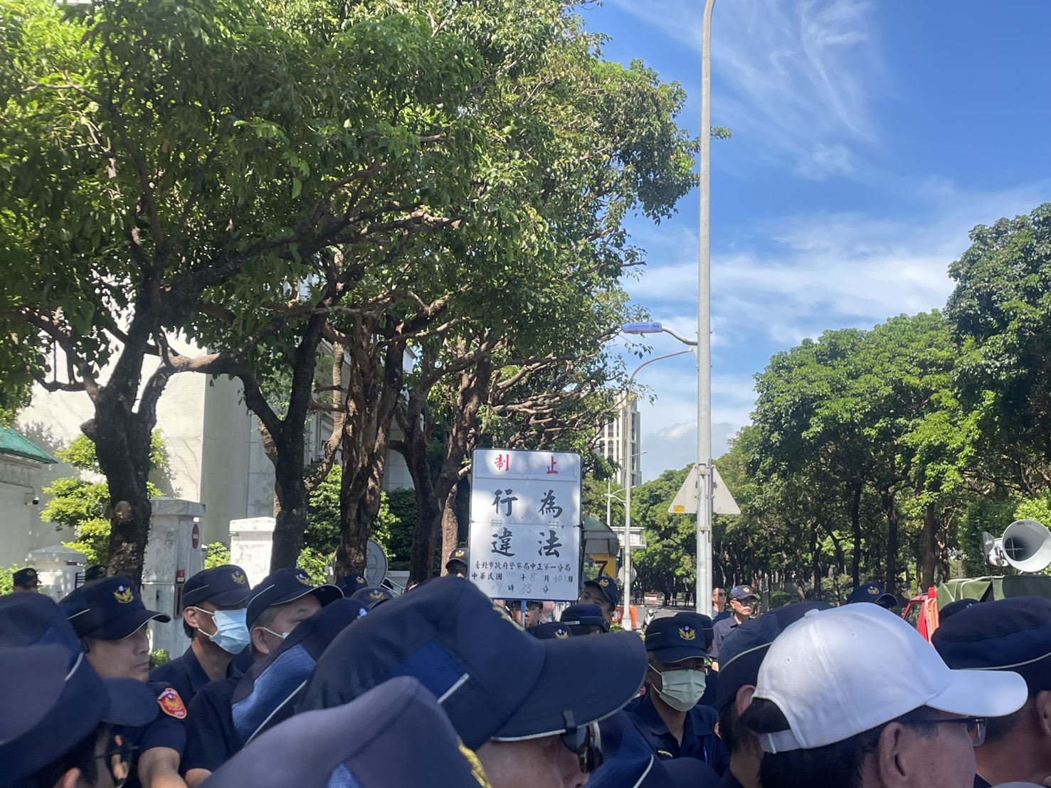因民眾黨公職與支持者試圖再度靠近，警方多次舉牌表示「行為違法」。圖/記者洪子苓攝