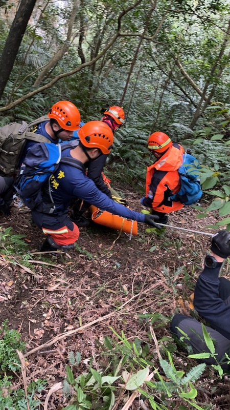 警消協力將跌落山崖的男子搬運下山送醫，然而男子最後仍宣告不治。圖/中央社