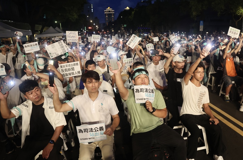 民眾黨8日晚間在立法院旁發起首場公民開講活動，現場支持者手持各式標語表達訴求。圖/中央社