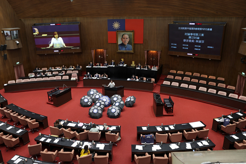 立法院會20日擬處理國民黨立法院黨團所提本會期延會至7月31日、反戒嚴公投等案，民進黨團在議場擺放「國會保護傘」字樣與國民黨徽的雨傘，批評藍營是因為怕罷免才意圖延長。圖/中央社