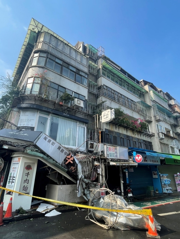 地震導致懸掛在外牆的水塔掉落，所幸未有人車受波及。圖/中央社