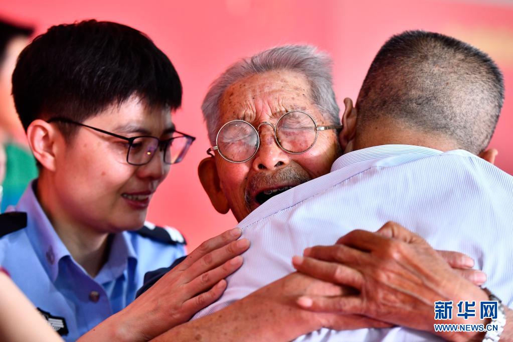 90歲高齡的羅鳳坤（中）緊摟著58年的兒子羅亞軍哭泣。圖/取自新華社