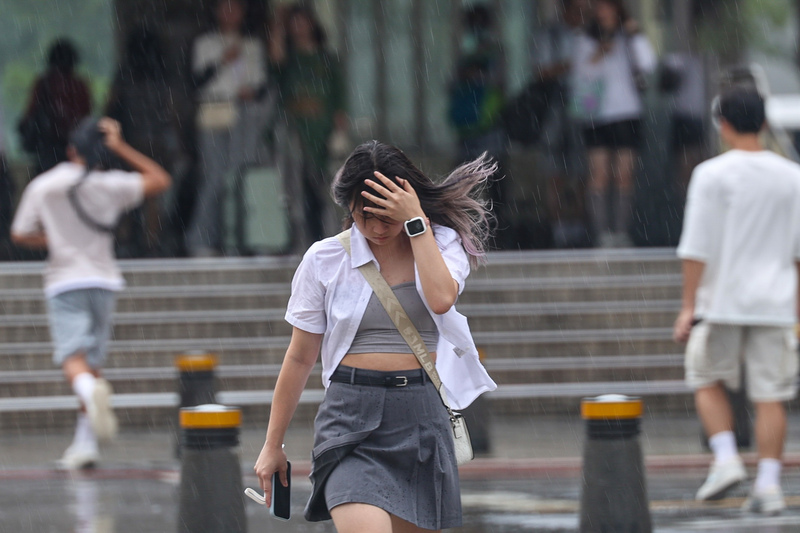 西半部地區午後有局部短暫雷陣雨，圖為西門町商圈街頭未攜雨具的民眾，冒雨前行。中央社