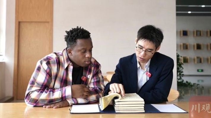 網紅張文（左）在成都大學圖書館內，翻查自己和家人的生活地蒲江縣的縣誌。圖/取自《川觀新聞》