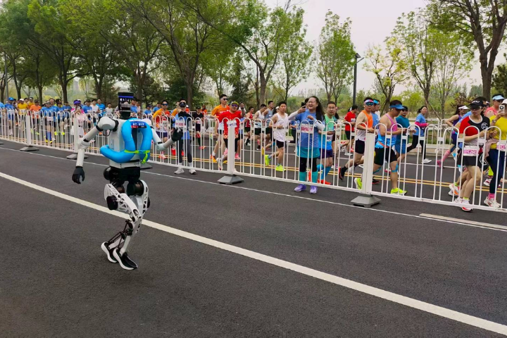 4月19日,半程馬拉松暨人形機器人半程馬拉北京亦莊舉行,圖為人類跑者在比賽過程中停下腳步,記錄機器人飛奔身影。圖/李嘉薇 攝