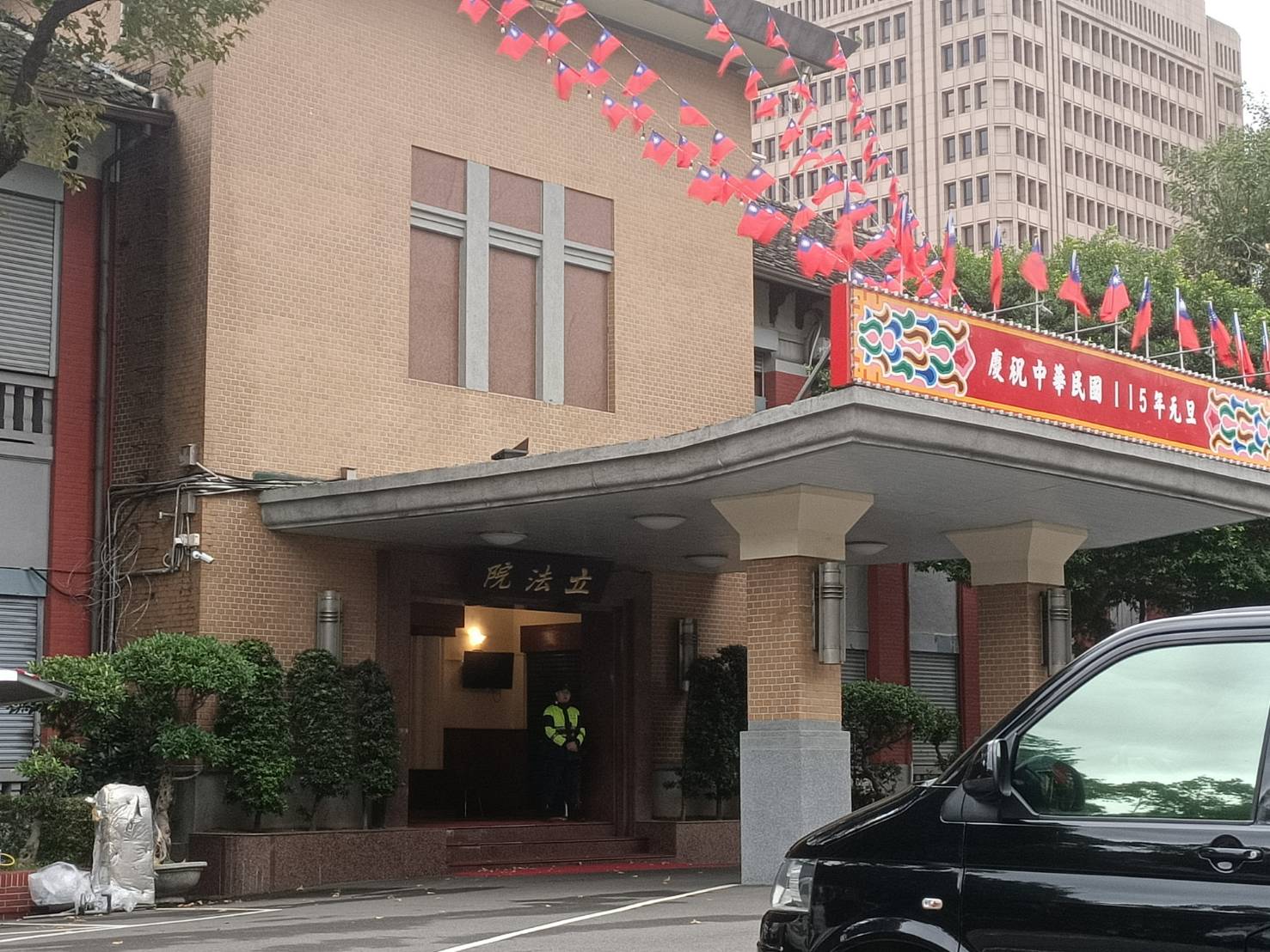 立法院入口門樓25日豎起紅底看板、插上小國旗、飾以國旗彩條，最有節慶氣氛，但看板上寫的是「慶祝中華民國115年元旦」。圖/記者簡立欣攝