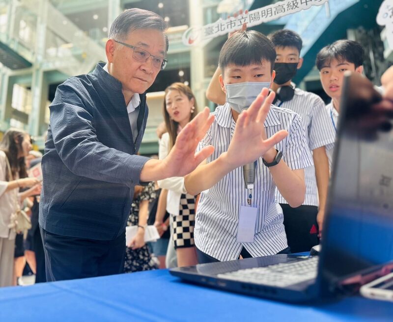 圖為台北市教育局長湯志民（左）15日與學生互動玩AI科技。圖/中央社
