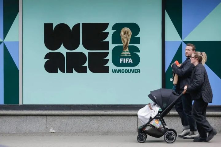 2026年2月26日,行人從加拿大溫哥華一棟建築外的2026年國際足總世界杯宣傳標識旁走過。圖/取自新華社