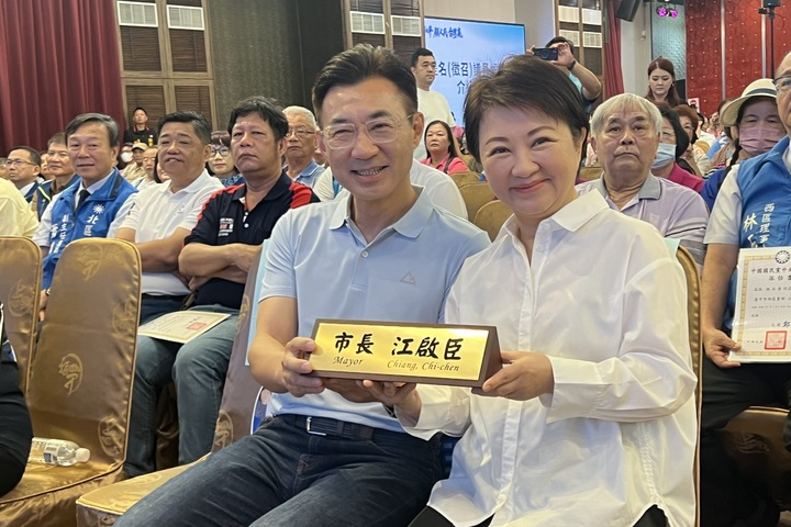 台中市長盧秀燕(右)4日特別準備了一個「正面刻有市長盧秀燕、反面刻有市長江啟臣」的特製市長室桌牌送給立法院副院長江啟臣(左)。圖/中央社