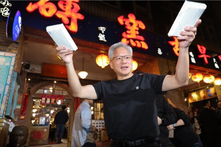   輝達執行長黃仁勳（前）31日晚間在台北宴請台灣供應鏈夥伴高層，黃仁勳在宴席中一度步出店外，親手發放餐盒給現場守候的記者。圖/中央社