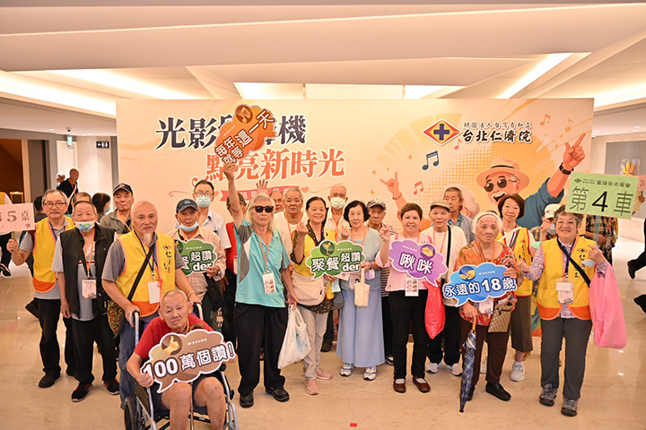 長者們手持趣味標語牌，在活動主視覺背板前開心合影。 圖／台北仁濟院 提供