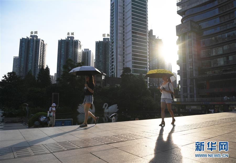 大陸民眾走過重慶市江北區觀音橋步行街（2018年7月19日攝）。當日，重慶市多個區縣的氣溫達40℃以上。圖/取自新華網